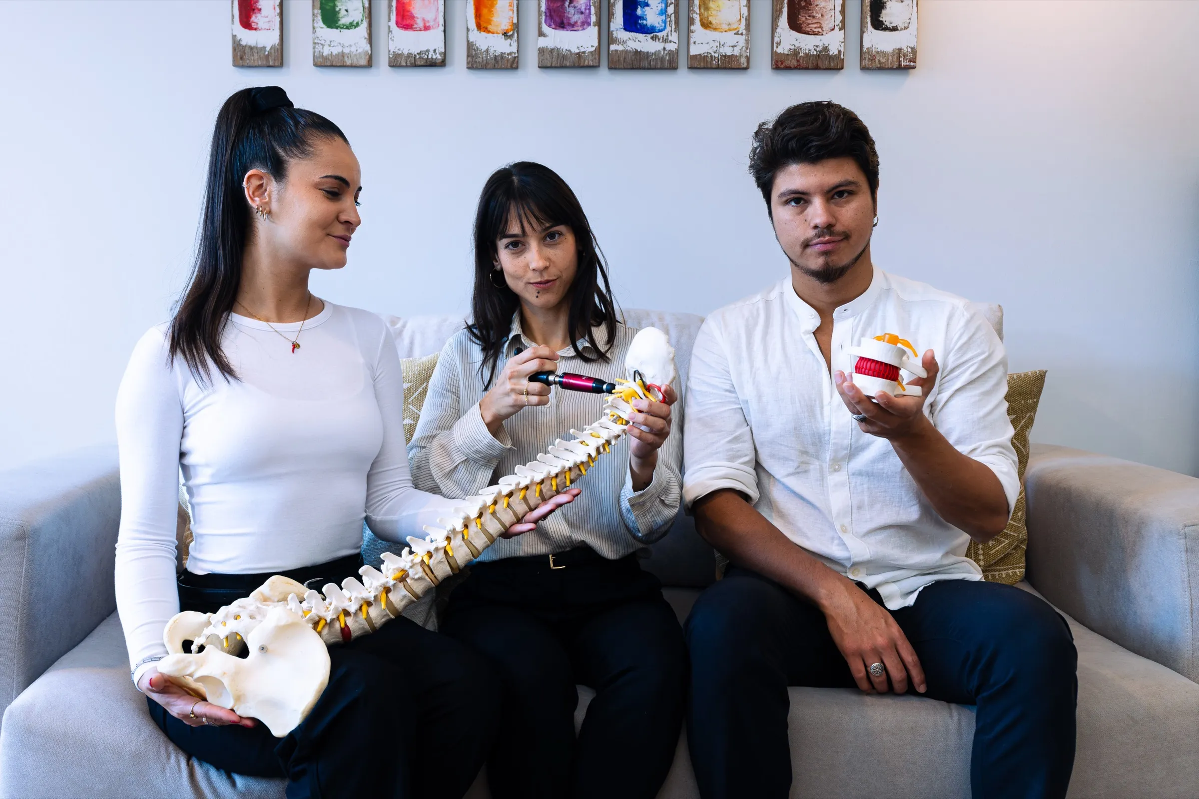 El equipo repasando modelos de columna y vértebras en el sofá del centro