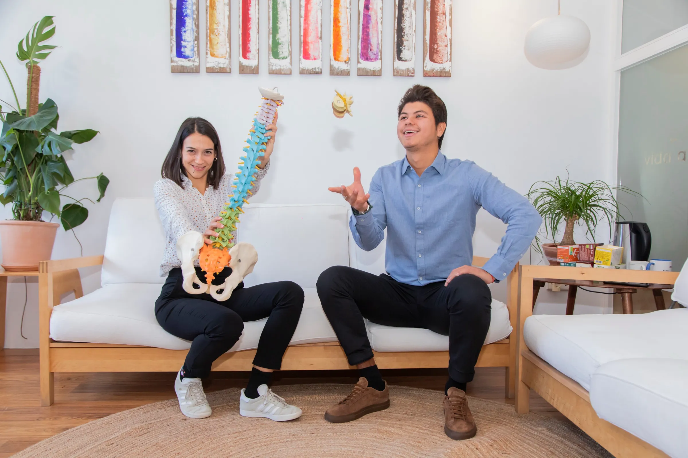 Dos miembros del centro bromeando con una columna vertebral didáctica en la sala de espera